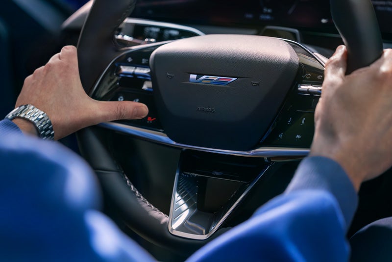Close-up of a Man About to Press the V-Button on the 2026 OPTIQ-V Steering Wheel | Russ Braunecker Auto Group in EFFINGHAM IL
